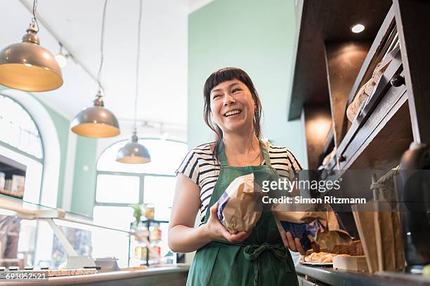 smiling female owner at counter in grocery store - small business stock pictures, royalty-free photos & images