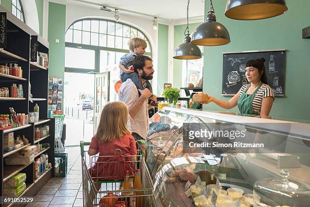 father with two children at deli counter in store - leanintogether stock pictures, royalty-free photos & images