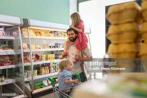 father with toddler girl and boy in grocery store - leanintogether stock pictures, royalty-free photos & images
