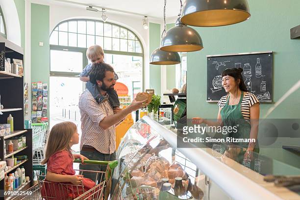 father with daughter and son at deli counter - leanintogether stock pictures, royalty-free photos & images