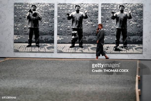 Woman walks past art work by Chinese artist Ai Weiwei titled "Dropping a Han Dynasty Urn" which is made with Lego bricks on the eve of the opening of...