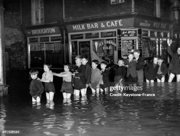 Les enfants se rangent en file indienne dans les rues inondées de leur ville la nuit pour être évacués vers des hébergements d'urgence le 23...