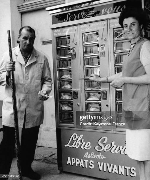 Monsieur Maillet et sa femme, commerçants, près du distributeur de boissons qu'ils ont transformé en distributeur d'asticots pour pêcheurs le 4 juin...