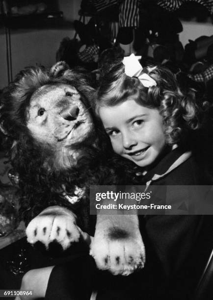 Une petite fille tient un lion en peluche dans un magasin de jouets.