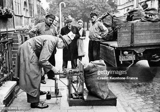 Contrôle du poids d'un sac de charbon dans la rue par la police, en Allemagne, le 28 septembre 1951.