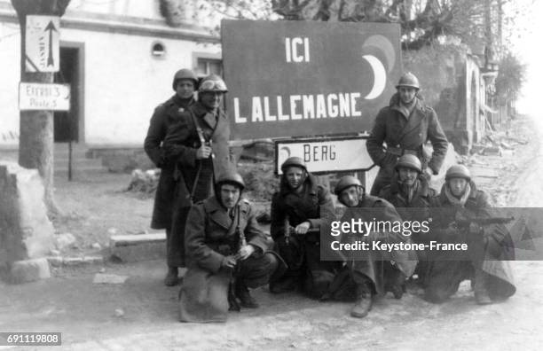 Des soldats français posent ave fierté devant un panneau de village allemand après avoir passé la frontière en 1945 en Allemagne.
