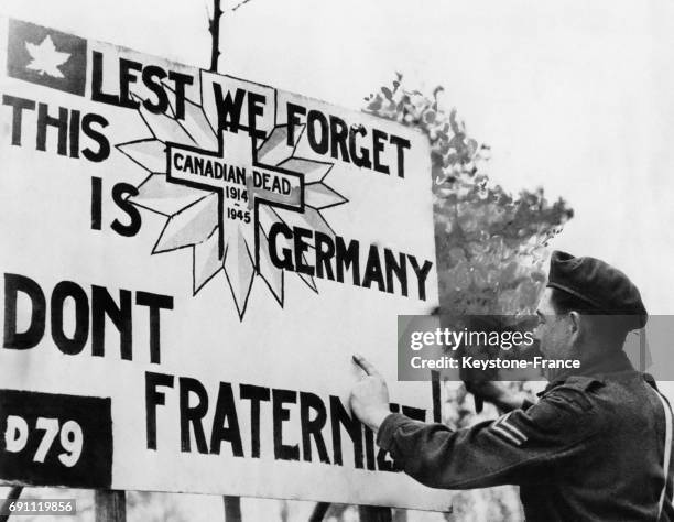 Un soldat canadien affiche un panneau soulignant aux troupes alliées que les Allemands sont des ennemis et qu'il ne faut pas fraterniser, 'Lest we...