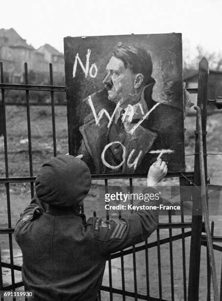Un soldat britannique écrit à la craie avec humour 'Pas de sortie' sur un portrait d'Adolf Hitler indiquant aux soldats que l'entrée du QG militaire...
