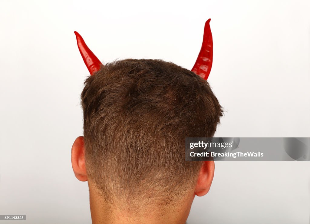 Red Chili Peppers On Head Of Man Against White Background