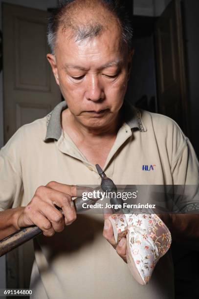 Artisan making shoes for "bound feet". Binding the foot of young girls was a tradition originated in the high classes of Chinese in order to keep the...