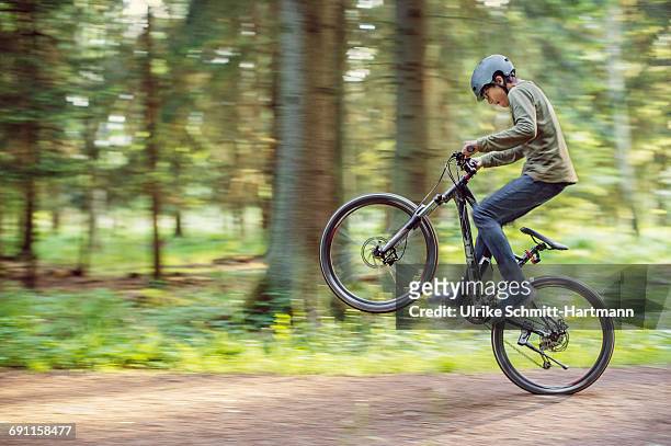 asian boy doing a wheelie on his bike - sólo niños varones fotografías e imágenes de stock