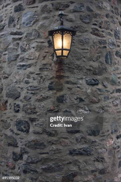 antique lighting fixture against old stone wall - antique lightbulb stockfoto's en -beelden