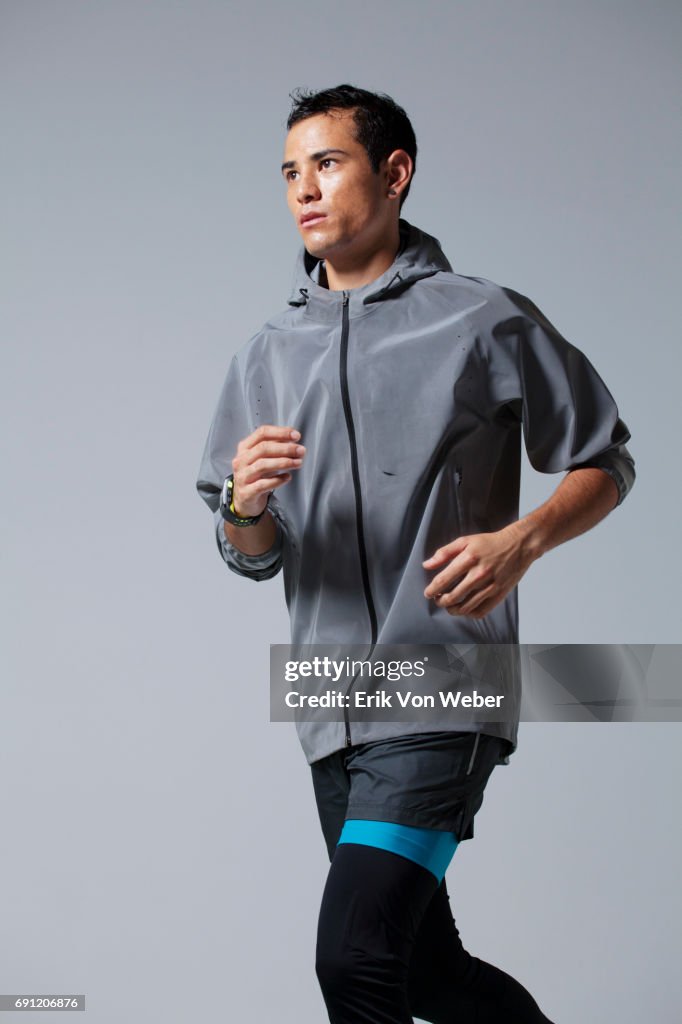 Man running on grey background wearing workout apparel
