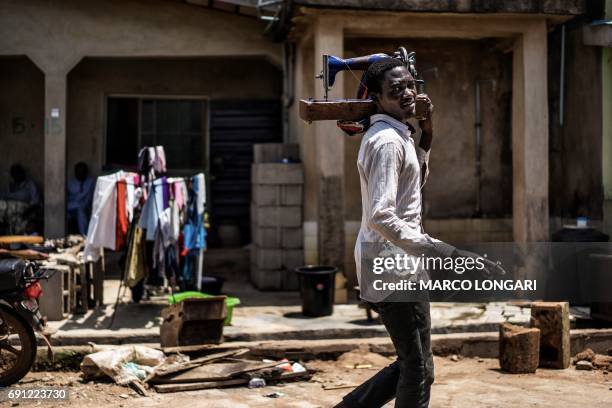 Man carries a sewing machine as he offers his tailoring services in Ojudu Berger, on June 01, 2017