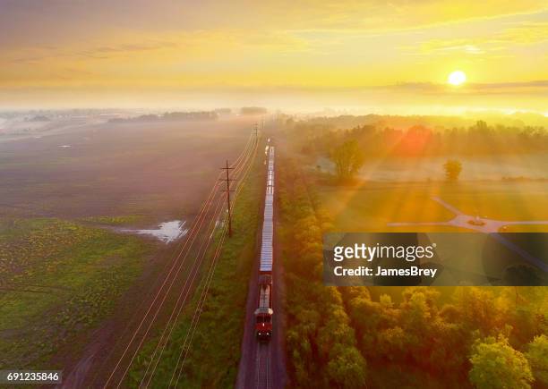 train rolls through foggy rural landscape at sunrise, aerial view - aerial train stock pictures, royalty-free photos & images