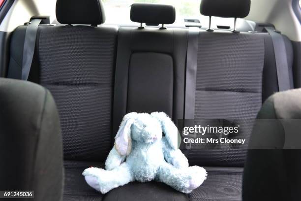 a plush toy bunny rabbit  on the back seat of a family car - rücksitz stock-fotos und bilder