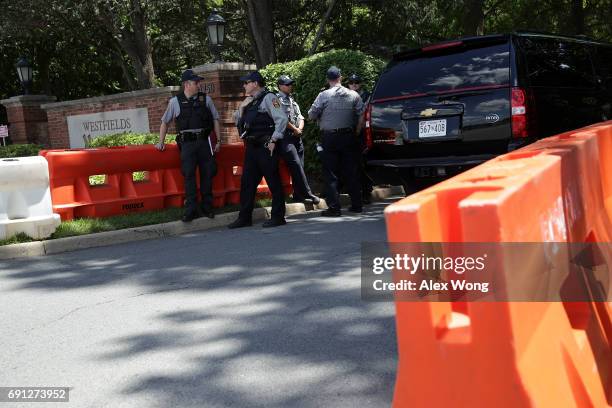 Members of Fairfax County Police stand guard at the entrance of Westfield Marriott Hotel where the Bilderberg Meeting takes place as a black SUV...