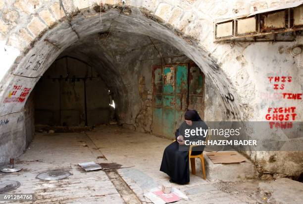 Palestinian woman sits in the old city of the West Bank city of Hebron on May 8, 2017. After half a century of occupation, Hebron remains an anomaly...