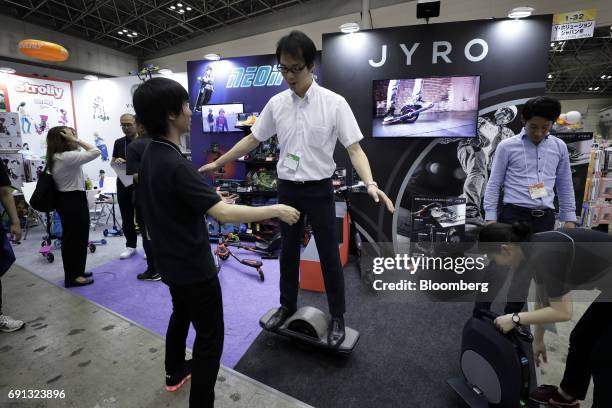Visitor, center, tries out the Jyro Roll self-balancing single-wheel electric skateboard at the Yvolution booth at the International Tokyo Toy Show...