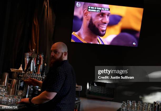 Bartender at The Chapel pour beers as Cleveland Caveliers LeBron James appears on a television during game one of the NBA Finals on June 1, 2017 in...