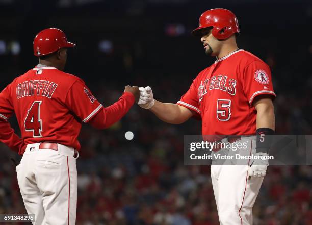 Albert Pujols of the Los Angeles Angels of Anaheim gets a fist bump from first base coach infield coach Alfredo Griffin after Pujols singled to left...