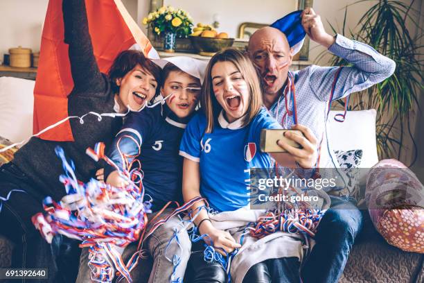 french cheering family watching soccer match on mobile on sofa - france supporter stock pictures, royalty-free photos & images
