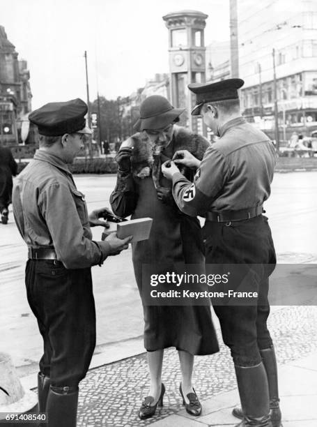 Des jeunes hommes des Jeunesses Hitlériennes collectent de l'argent en échange d'une récompense épinglée à la boutonnière d'une dame sur la Potsdamer...