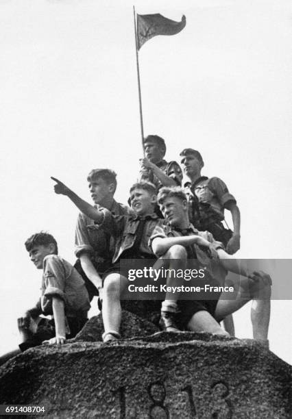 Des garçons membres des Jeunesses Hitlériennes assis sur un monument commémoratif pointent du doigt vers l'horizon le 20 mai 1938 en Allemagne.