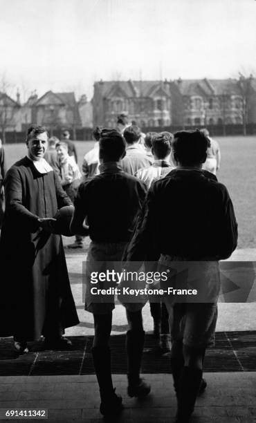 Frère David remettant un ballon de football à ses élèves pour un entraînement sportif, au Saint Joseph's College, circa 1950, à Londres, Royaume-Uni.