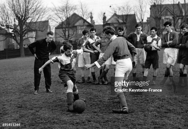 Les footballeurs professionnels George Smith et Archie Macaulay prodiguant des conseils aux jeunes joueurs du Saint Joseph's College, circa 1950, à...