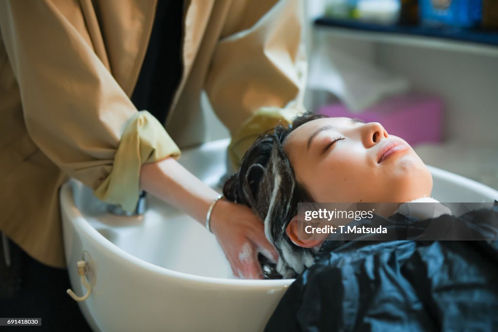 A man's hairdresser shampoo a young woman