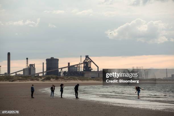 Youths stand on Redcar Beach, in front of a backdrop of the shuttered Teesside Steelworks, formally operated by Sahaviriya Steel Industries Pcl, in...
