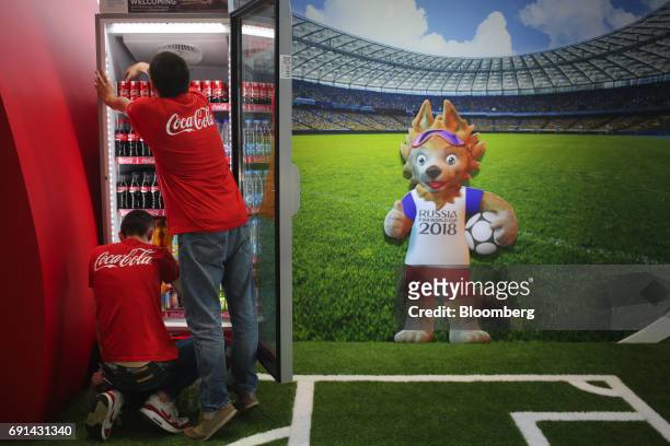 Workers restock a fridge cabinet with drinks at the Coca-Cola Co. Booth promoting the Russia 2018 soccer world cup tournament during the St....