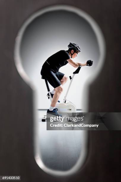 spying through the keyhole  on a guy riding an exercise bike - key hole stock pictures, royalty-free photos & images