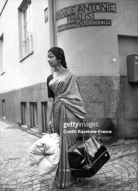 Cette jeune femme porte, outre un sac, un duvet en plumes enroulé pour supporter les températures froides de la région, en Allemagne, le 24 juin 1967.