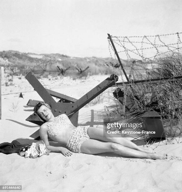 Jeune femme en maillot de bain allongée sur le sable de la plage du Touquet, France en 1946.