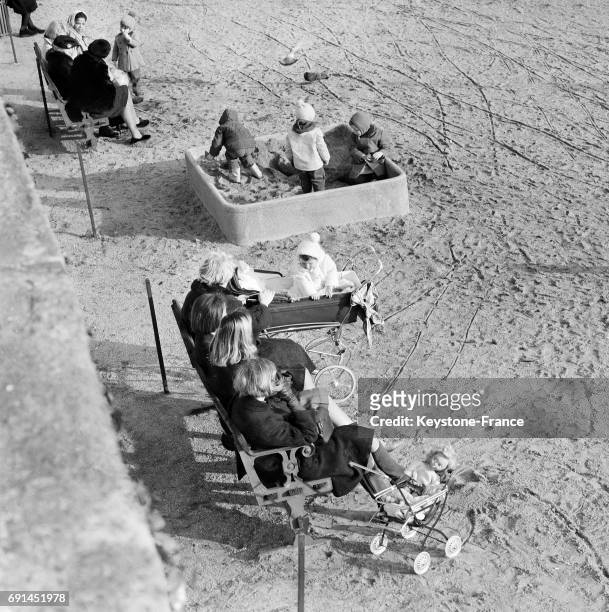 De jeunes mamans prennent le soleil en regardant jouer leurs enfants au Jardin des Tuileries à Paris, France le 16 janvier 1968.