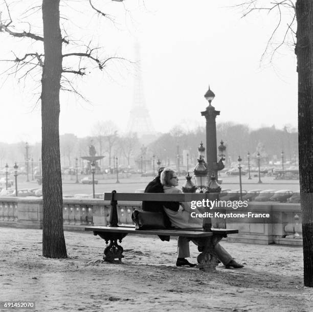 Couple d'amoureux prennent le soleil sur un banc au Jardin des Tuileries à Paris, France le 16 janvier 1968.