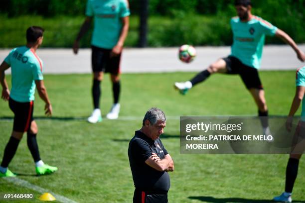 Portugal's head coach Fernando Santos looks down as players train during a training session at "Cidade do Futebol" training camp in Oeiras, outskirts...