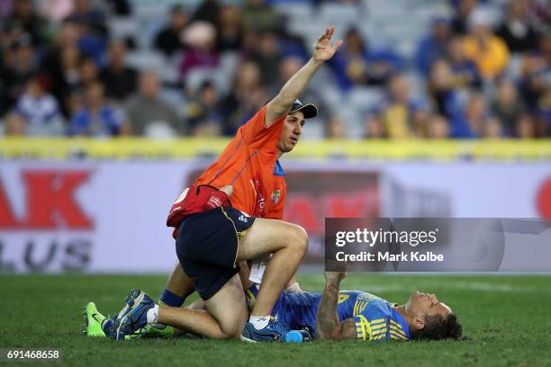 The trainer signals to the bench as Josh Hoffman of the Eels lies injured on the ground during the round 13 NRL match between the Parramatta Eels and...