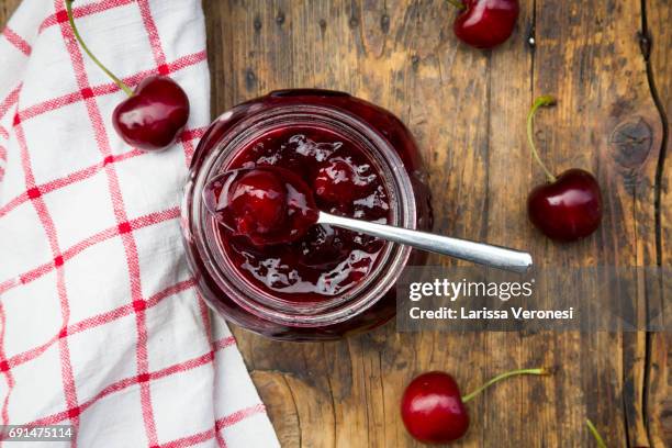 jar of homemade cherry jam and cherries on wood - kersenjam stockfoto's en -beelden