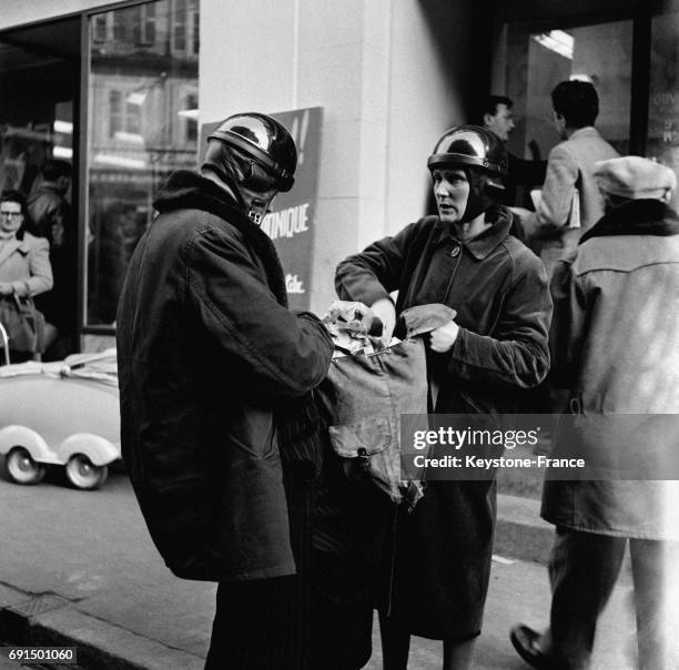 Un couple, casque de moto sur la tête, rangent leurs courses dans le sac à dos, à Dole, France le 2 mars 1953.