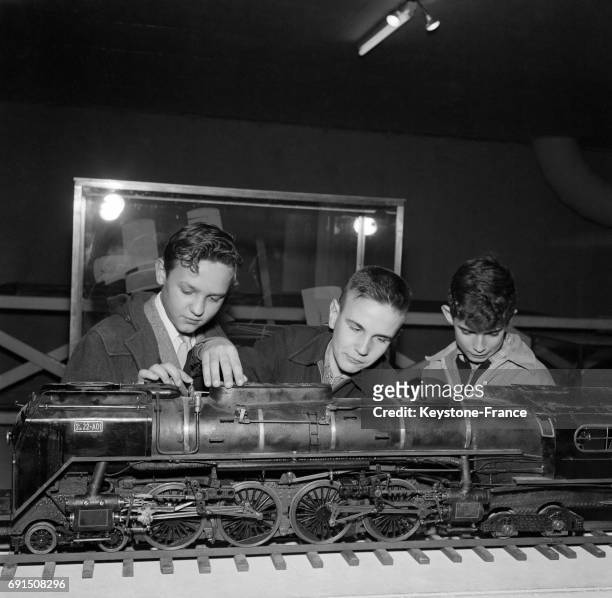 De jeunes garçons regardent avec beaucoup d'attention une locomotive en modèle réduit, à Paris, France le 8 octobre 1954.