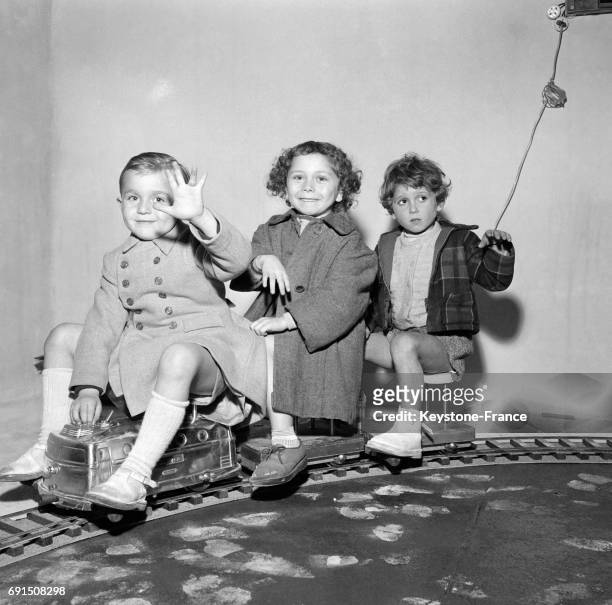 Trois enfants s'amusent assis sur un train en modèle réduit, à Paris, France le 8 octobre 1954.