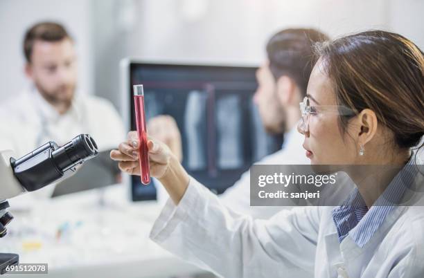 scientist looking at test tube - hematology stock pictures, royalty-free photos & images