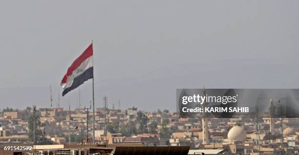 An Iraqi flag flutters above a neighbourhood of west Mosul on June 2 during the ongoing offensive by Iraqi forces to retake the city from Islamic...