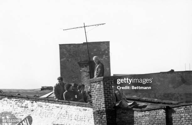 As police officer watches, Jerry Riccia , co-owner of store under siege and mastermind of the escape, sits with fellow hostages as they await rescue...