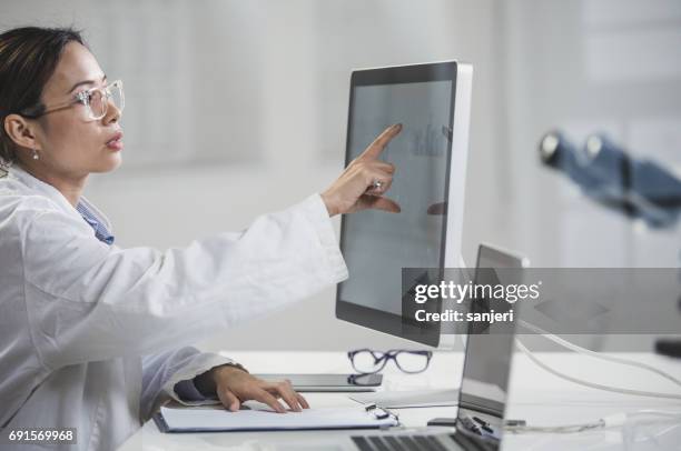female doctor pointing at computer monitor - electronic medical record stock pictures, royalty-free photos & images
