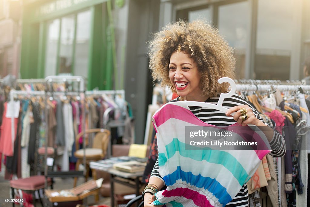 Woman laughing while trying on clothes at market
