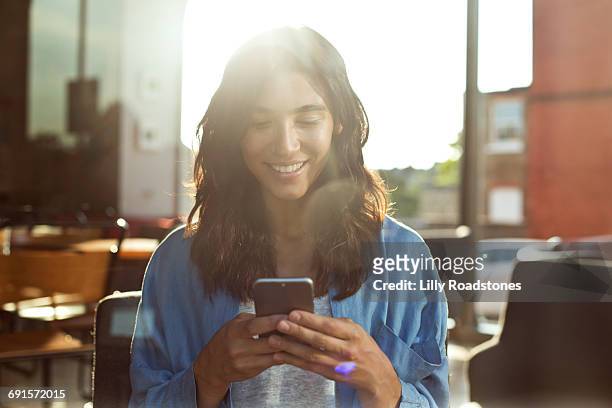 young woman using mobile phone in coffee shop - portable information device foto e immagini stock